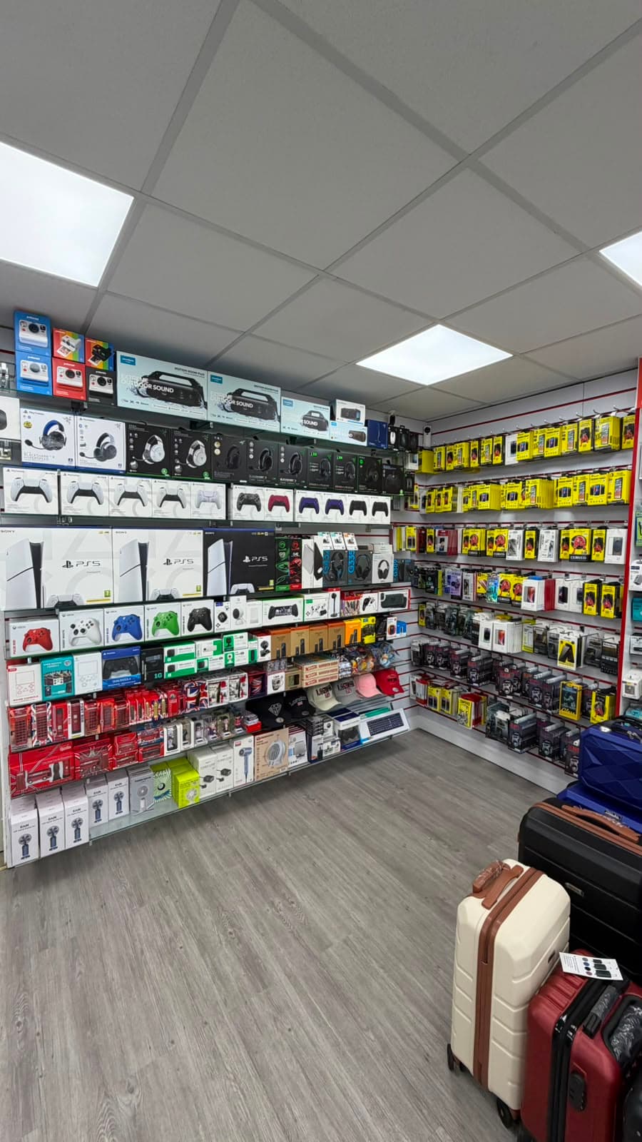 Greenwich Gadgets interior — gaming consoles, controllers and travel luggage